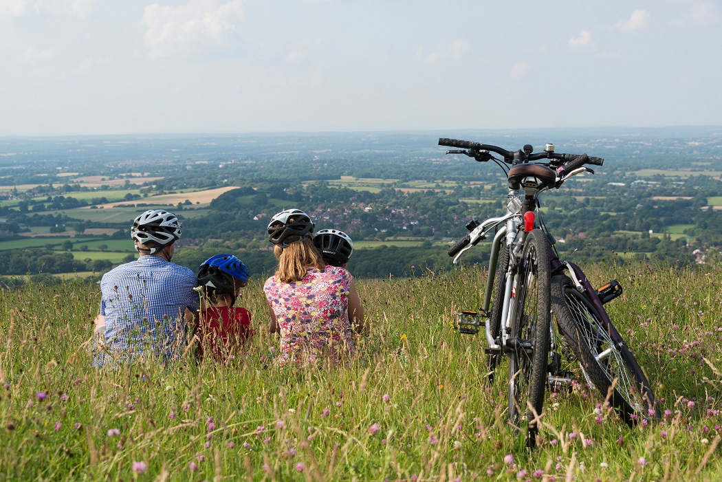 Family sat on hill at Ditchling Beacon overlooking the South Downs. Bicycles to the side of them.