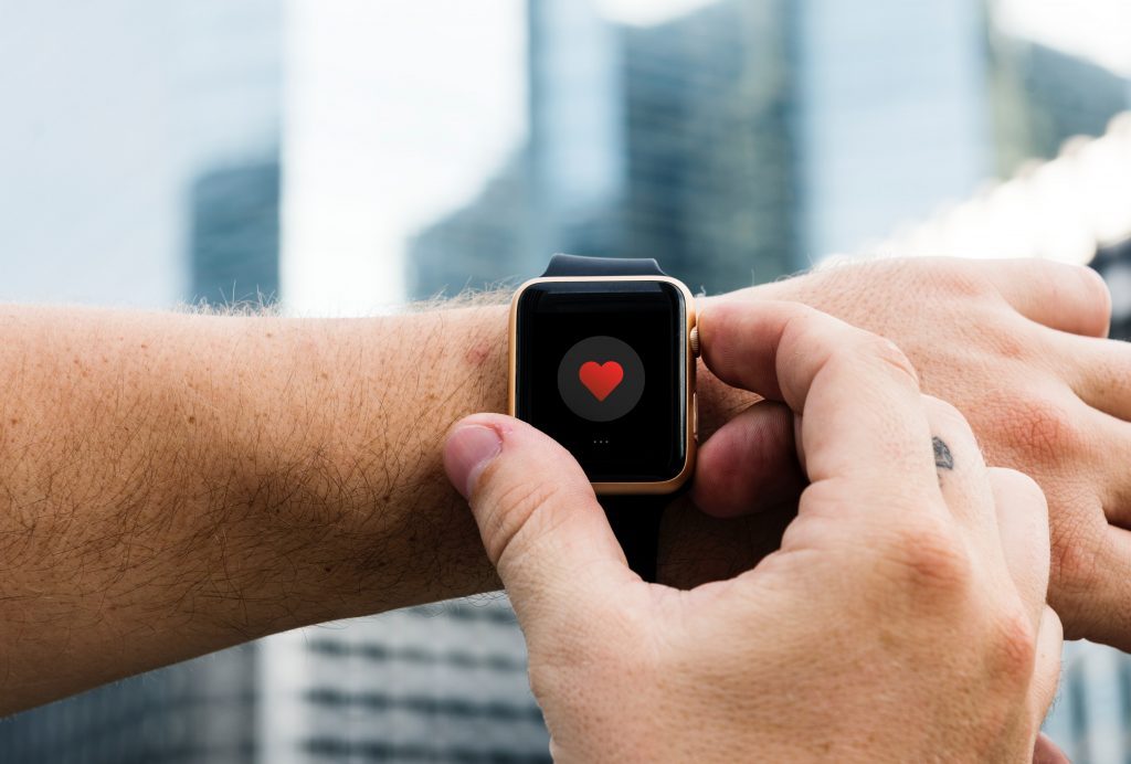 Adult wrist with smart watch on, displaying a red heart