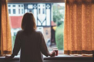 Rear view of woman at home looking out the window
