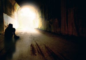 The silhouette of a teenage boy alone in a tunnel.
